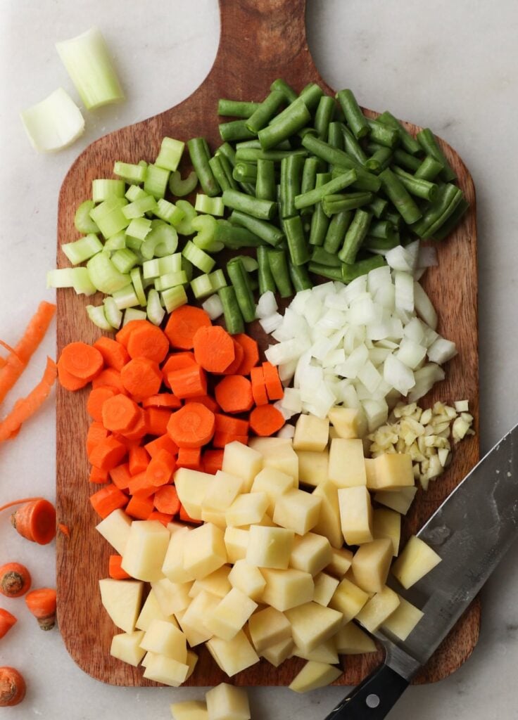 chopped and diced vegetables on a wooden cutting board.
