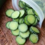 Frozen sliced cucumbers spilling out of in a plastic freezer bag.
