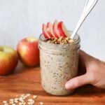 A hand holding a mason jar with apple pie overnight oats.