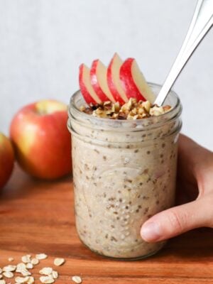 A hand holding a mason jar with apple pie overnight oats.