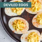 A plate of classic deviled eggs topped with paprika sits on a gray countertop, beside a jar of apple pie overnight oats for a delicious pairing.