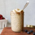 A mason jar filled with overnight oats, topped with banana slices and peanut butter.
