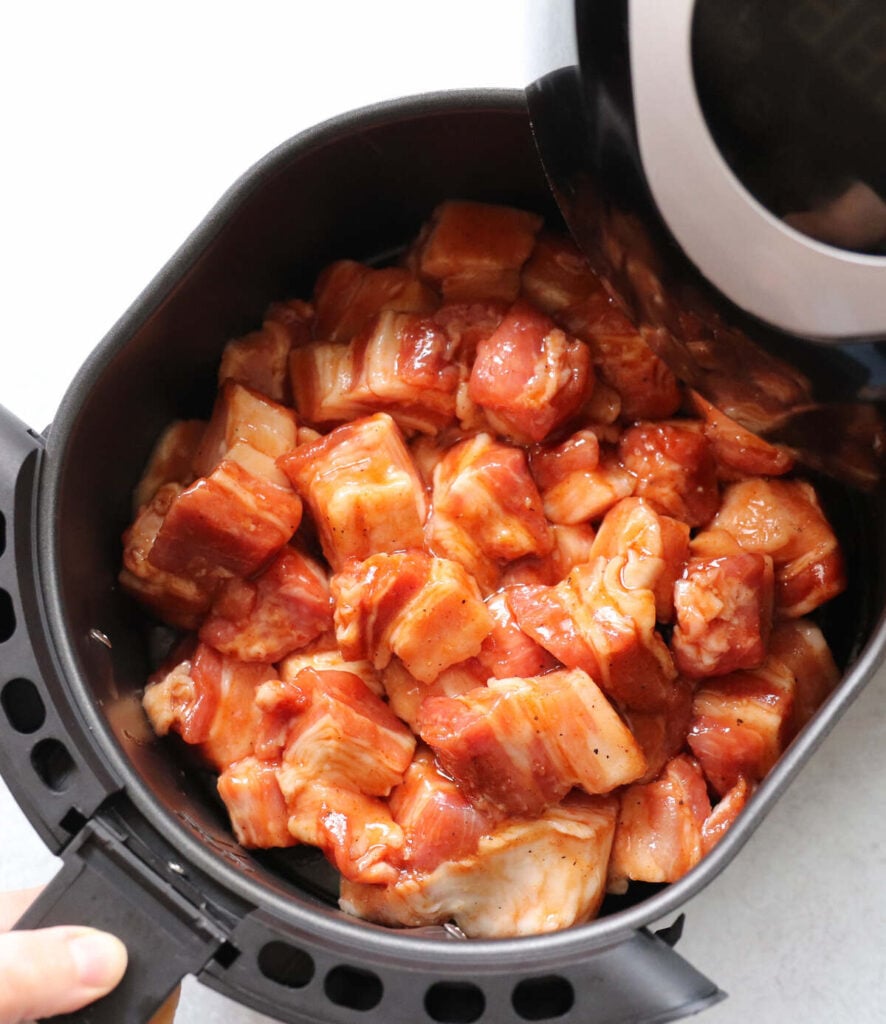 Pork belly bites in air fryer basket, before cooking.