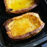 Close up of two halved spaghetti squashes in an air fryer basket.