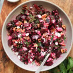 A gray bowl filled with beetroot and feta salad, garnished with fresh herbs.