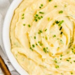 Dairy-free mashed potatoes in a white bowl topped with chives.