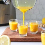 Ginger Lemon Turmeric juice pouring into a shot glass.