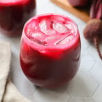 A glass filled with ice and pink beet carrot apple juice.