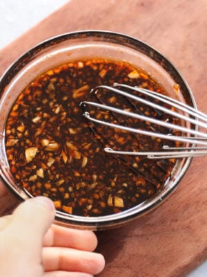 Whisking soy sauce marinade ingredients together in a small glass bowl, viewed from overhead.