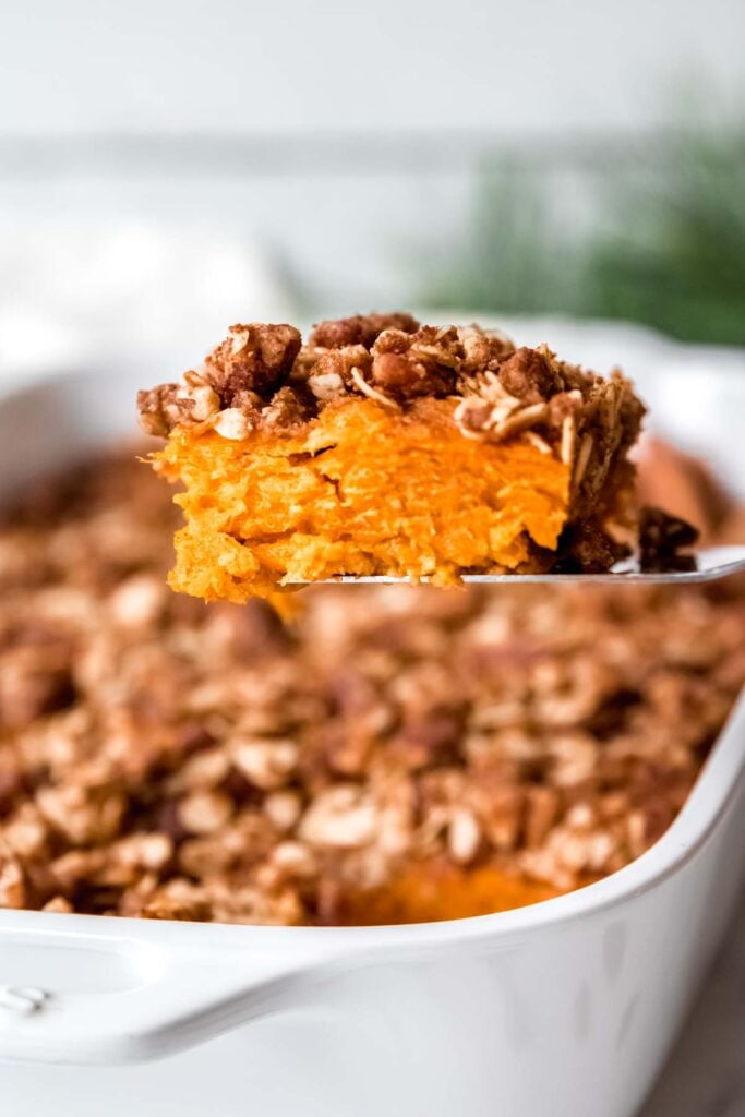 Serving spatula holding a lighter holiday side dish of healthy sweet potato casserole.