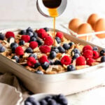 A white casserole dish filled with gluten free French toast bake topped with berries.