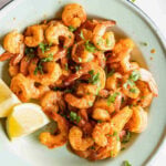 Frozen shrimp cooked in the air fryer plated with lemon wedges.
