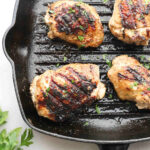 Greek yogurt marinated chicken in a cast iron skillet.