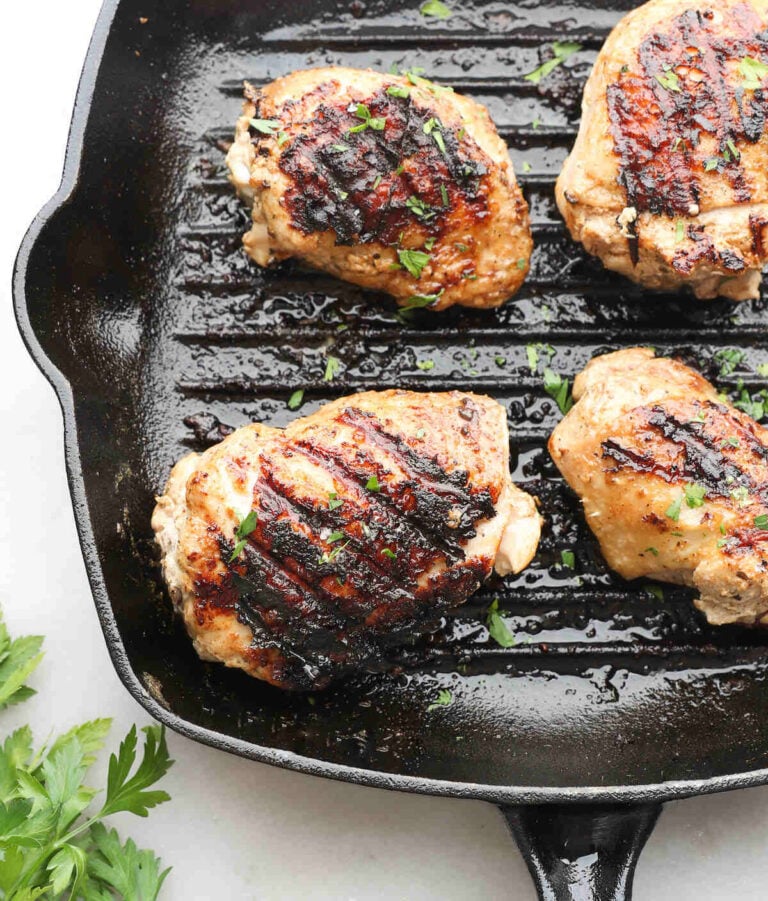 Greek yogurt marinated chicken in a cast iron skillet.
