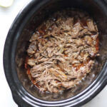 A Chipotle Copycat crock pot full of Whole30 Barbacoa seasoned meat, infused with tangy limes.