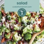 A bowl of broccoli bacon salad with red onions and dressing sits beside a wooden spoon. The text above reads "Broccoli Bacon Salad," offering a taste as satisfying as your favorite pork chop marinade. Visit our website for more.