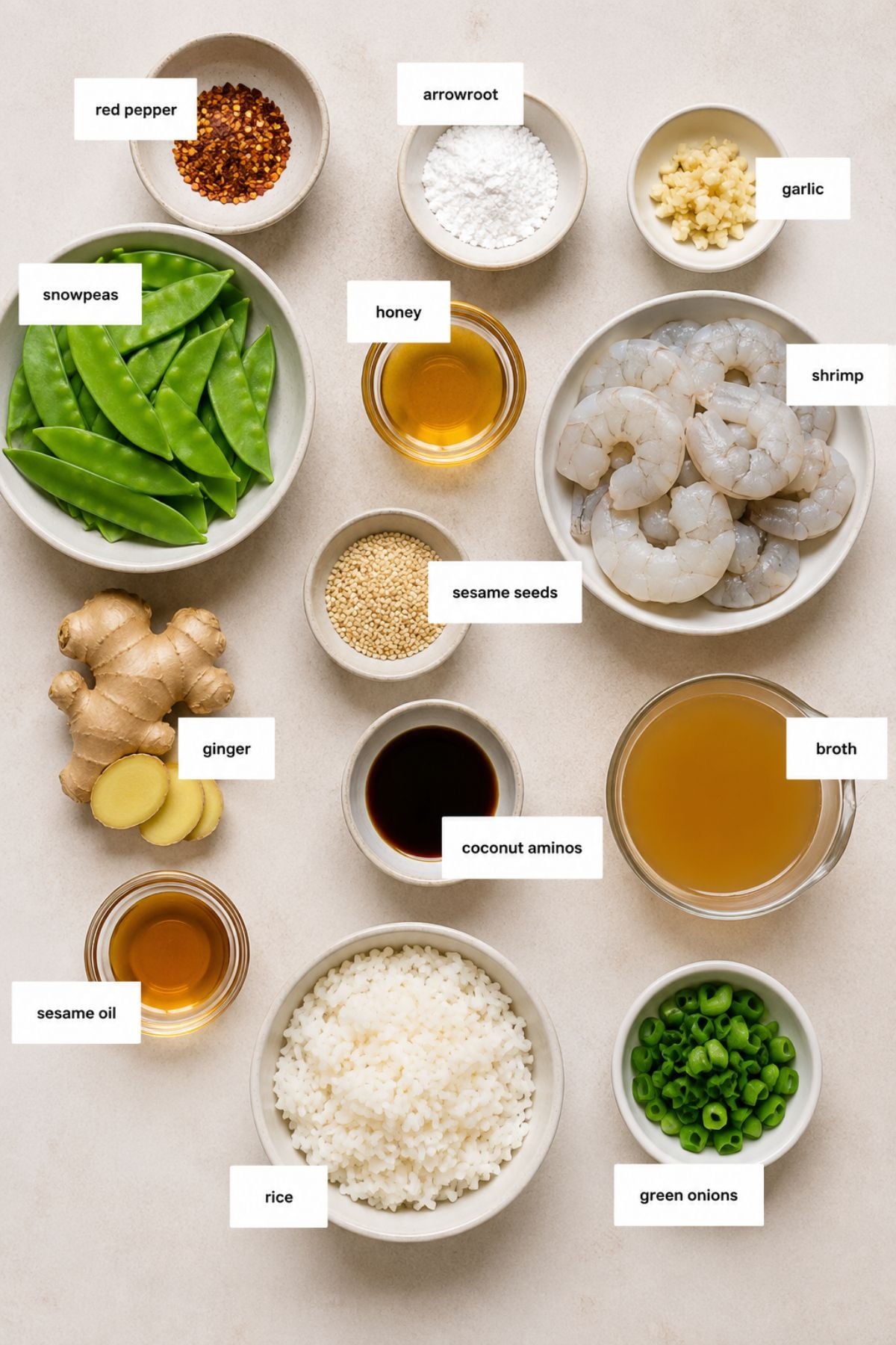 Assorted labeled ingredients in bowls on a light surface, including shrimp, snow peas, rice, green onions, broth, honey, garlic, ginger, sesame oil, red pepper flakes, arrowroot, and coconut aminos.