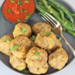 A gray plate with air fryer meatballs, marinara sauce and green beans.