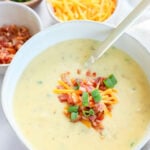 Instant Pot potato soup in a white bowl with a spoon.