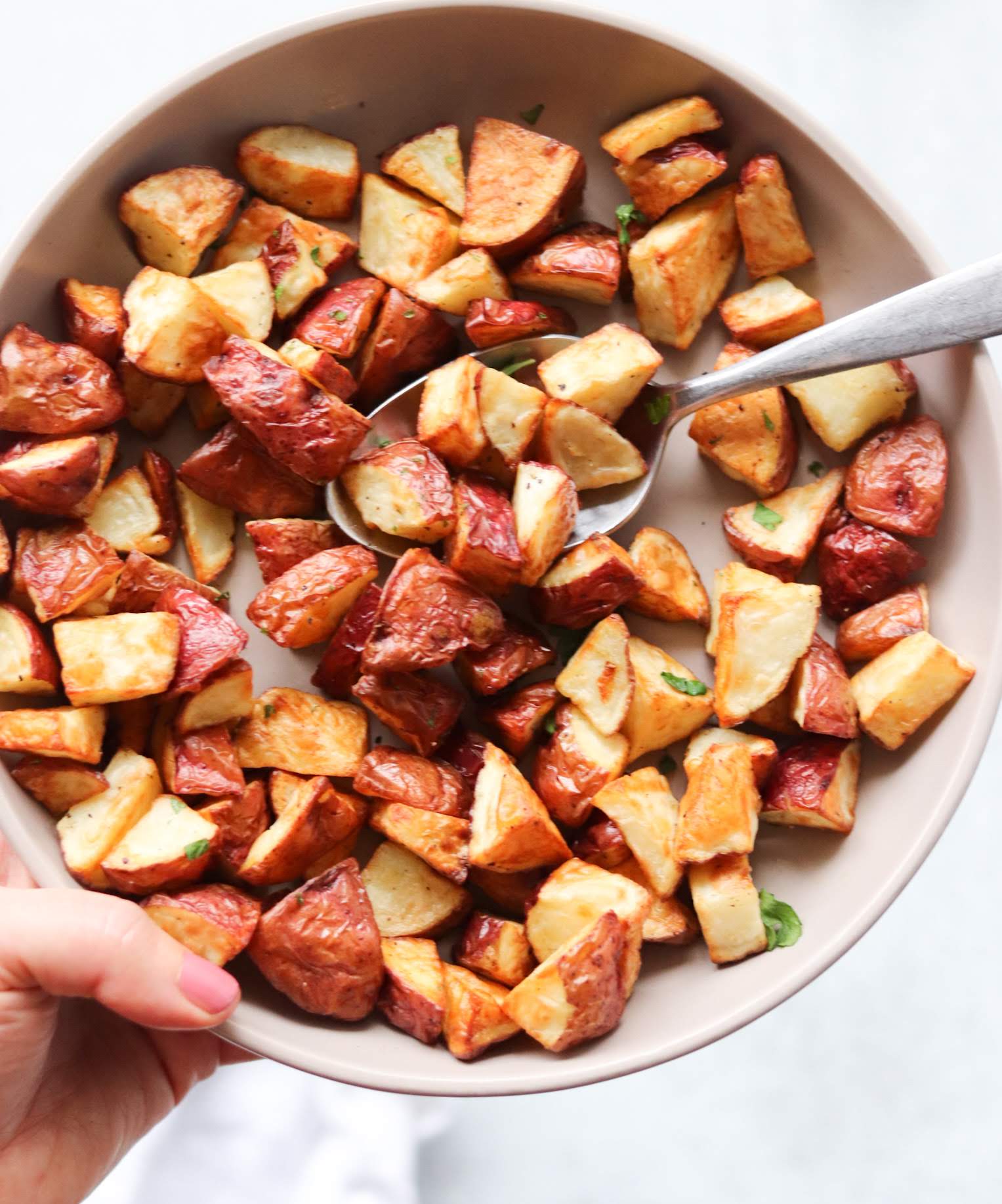 A bowl of roasted red potatoes in a large serving bowl.