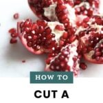 A sliced pomegranate with exposed seeds on a white surface, accompanied by the text "How to cut pomegranate—cook at home mom.