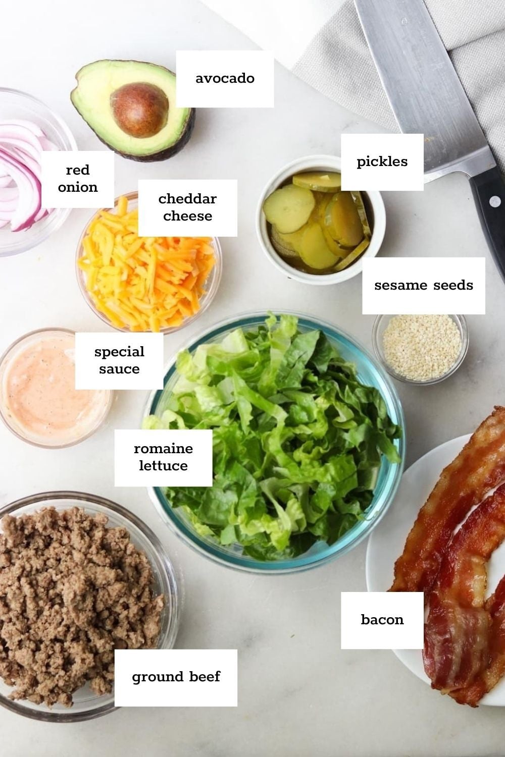 Prepped ingredients in glass bowls to make a Big Mac-inspired salad.