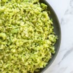 A plate of finely chopped broccoli on a marble surface.