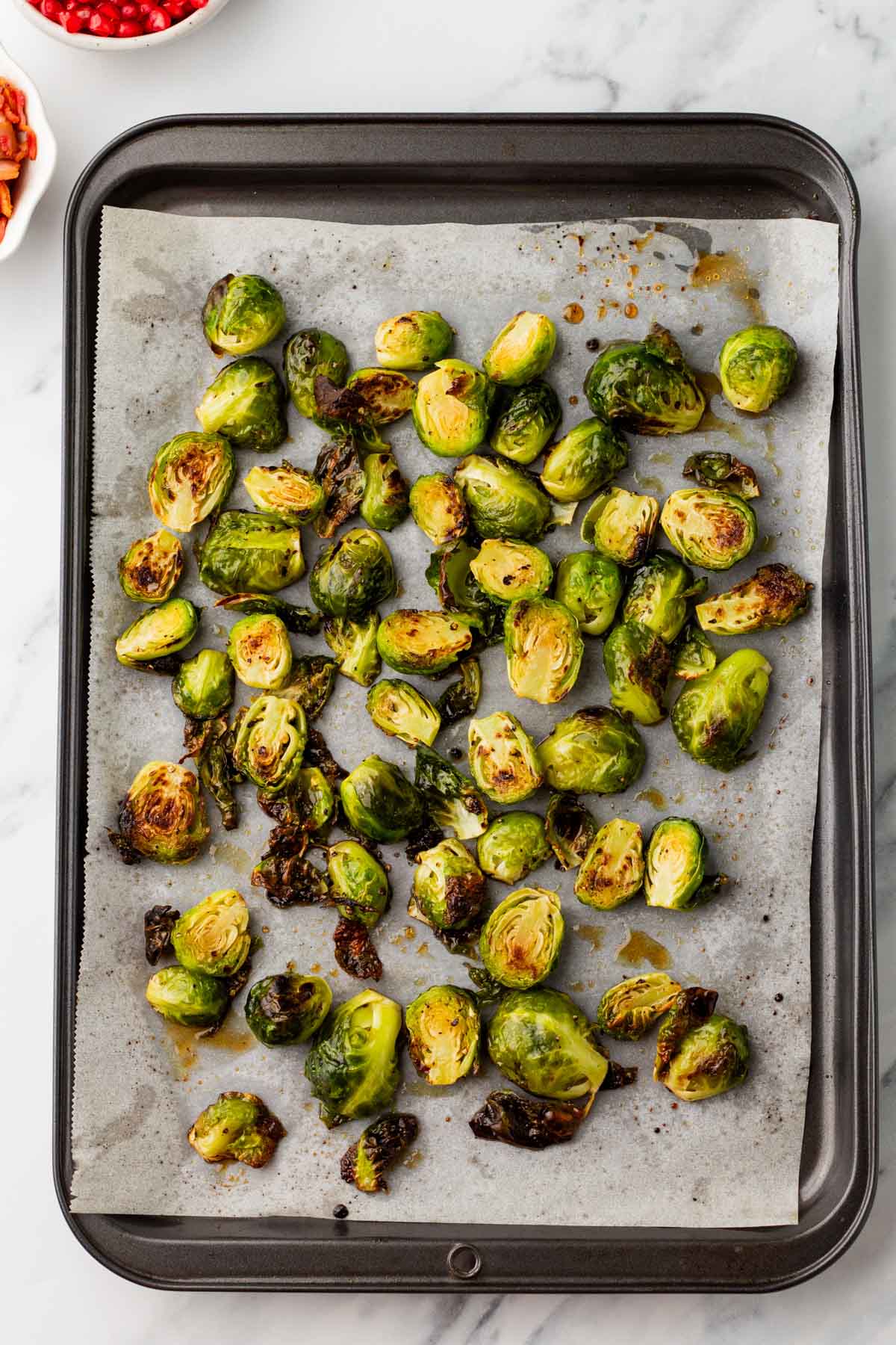 Sheet pan of roasted Brussel sprouts on parchment paper.
