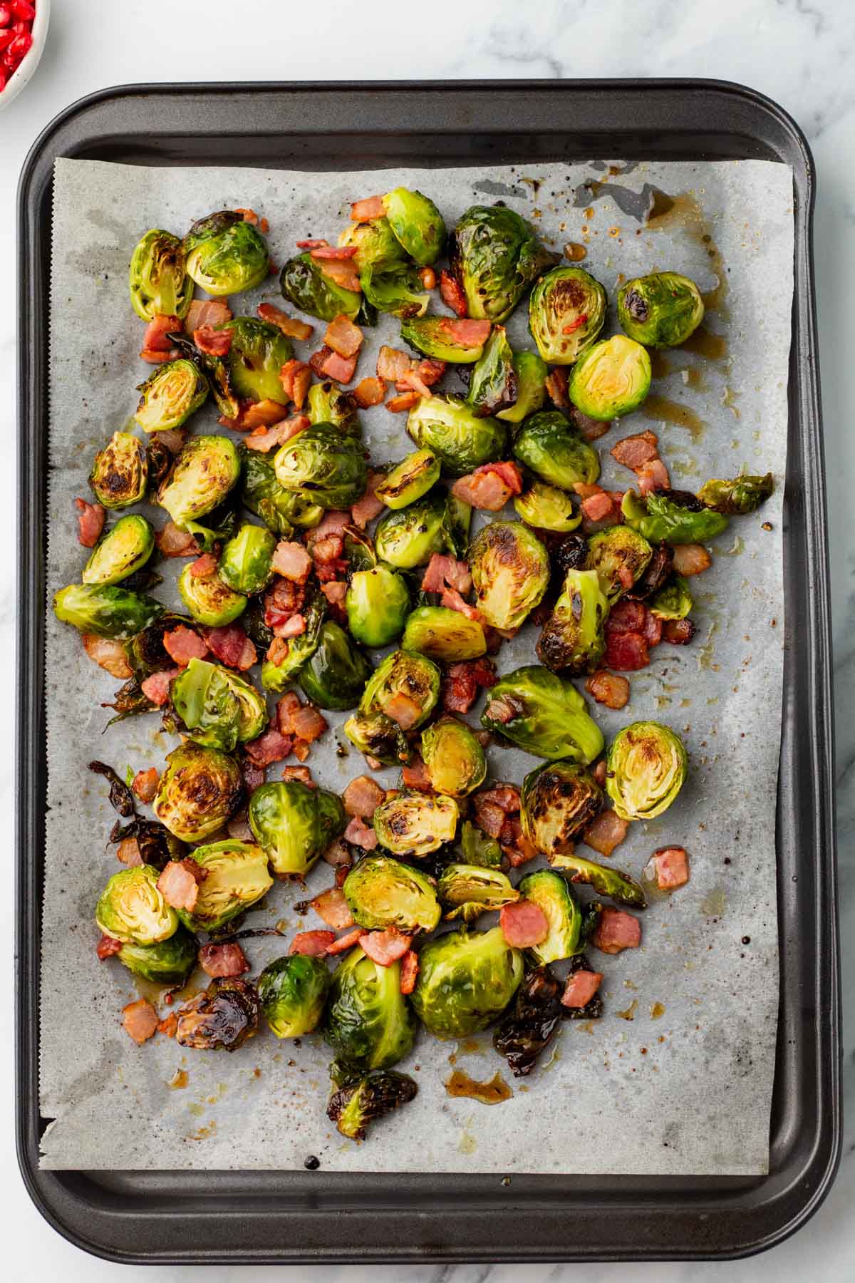 Maple bacon Brussel sprouts on a sheet pan lined with parchment paper.