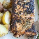 Roasted salmon with Italian seasoning on a plate, served with roasted potatoes and asparagus.