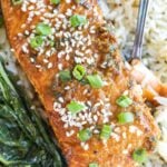 Soy ginger salmon topped with sesame seeds and chopped scallions, served with steamed greens and rice.