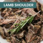 Shredded slow-cooked lamb shoulder with a hint of ranch chicken seasoning, garnished with a sprig of rosemary in a white bowl.