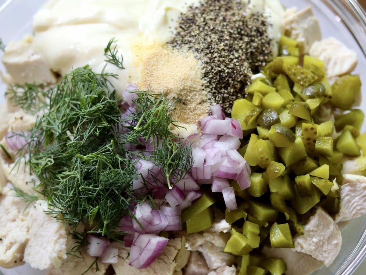 Bowl with unmixed ingredients for a chicken salad recipe.