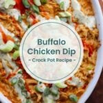 Close-up of buffalo chicken dip in a white baking dish, topped with ranch dressing, hot sauce, and green onions. Perfect for game night or pairing with a refreshing paloma mocktail. Text overlay reads, "Buffalo Chicken Dip - Crock Pot Recipe.