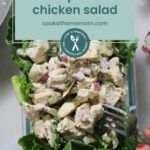 A glass container filled with dill pickle chicken salad on a bed of lettuce, resembling a marinated vegetable salad, with a fork and a text overlay reading "dill pickle chicken salad cookathomemom.com.