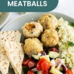 A plate with flavorful Greek chicken meatballs, white rice, pita bread slices, and a side of fresh tomato-cucumber salad.