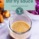 A glass jar of stir fry sauce sits on a countertop next to a bowl of chopped red cabbage and a plate of cooked chicken pieces. The label clearly displays "stir fry sauce," ready to add bold flavor to your meal.