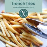 Plate of cooked French fries with metal tongs, overlaid with text that reads “air fryer frozen french fries cookathomemom.com,” similar to how you might prepare oven baked salmon in foil for an easy homemade meal.