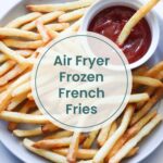 A plate of air-fried frozen French fries with a small bowl of ketchup, one fry being dipped, and text overlay reading "Air Fryer Frozen French Fries"—the perfect quick snack to pair with oven baked salmon in foil.