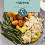 A plate of shredded Mississippi chicken, roasted potatoes, green beans, and pepperoncini sits next to a serving dish of potatoes. Try pairing this meal with oven baked salmon in foil for a delicious dinner spread. Text overlay reads "mississippi chicken.