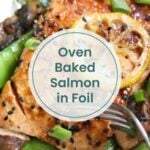Close-up of oven baked salmon in foil, topped with lemon slices, black sesame seeds, and green onions, served with snow peas and mushrooms on the side.