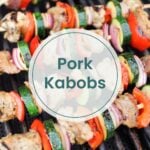 Skewers of pork, zucchini, red onion, and red bell pepper grilling on a barbecue with a text overlay that reads "Pork Kebabs.