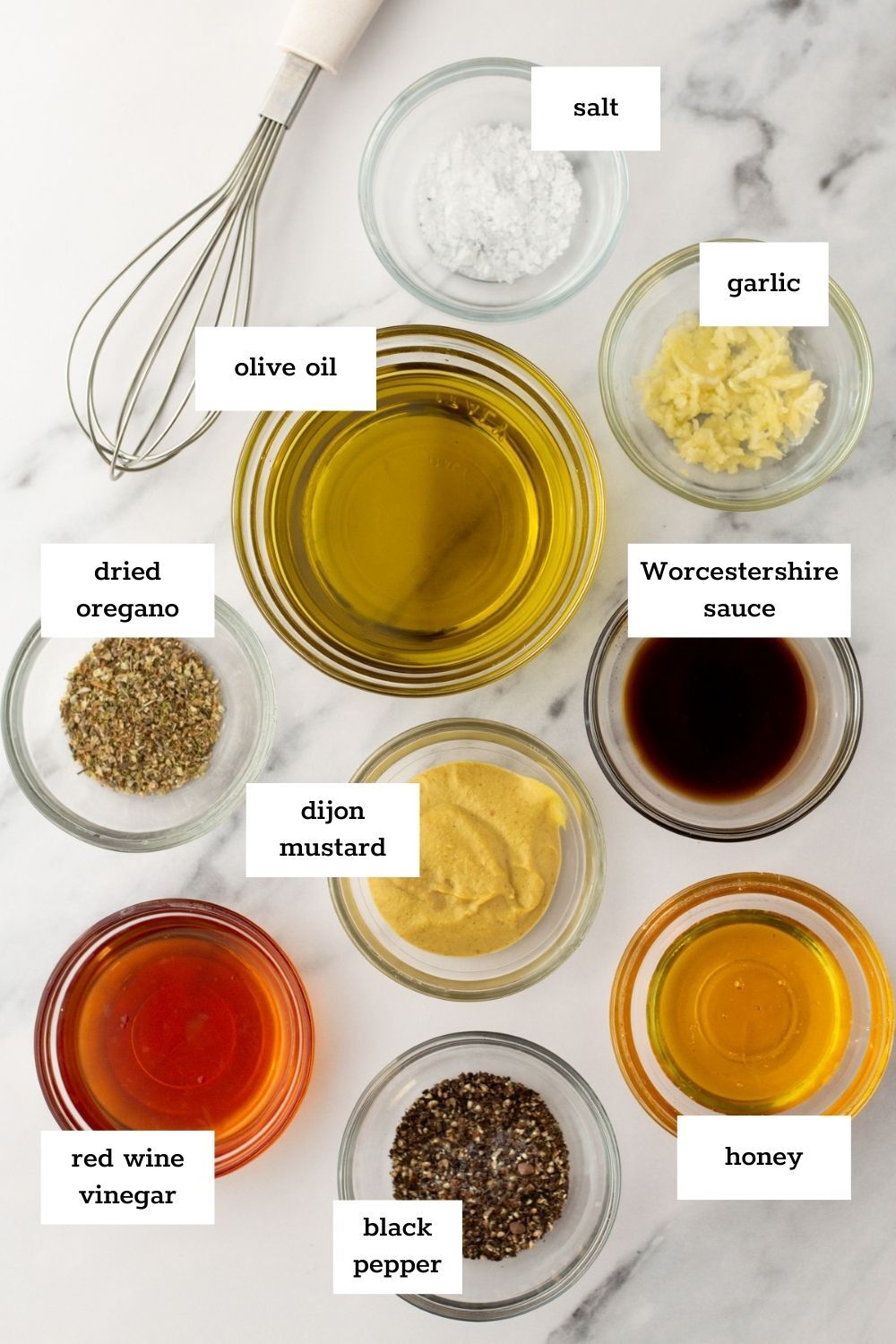 Various labeled ingredients for salad dressing, perfect for crafting a flavorful dijon vinaigrette—featuring olive oil, garlic, salt, black pepper, honey, red wine vinegar, Dijon mustard, dried oregano, and Worcestershire sauce.