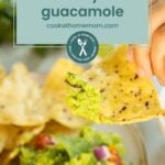 A hand dips a tortilla chip into a bowl of easy guacamole, garnished with diced red onions and tomatoes. Text overlay reads: "easy guacamole, cookathomemom.com.