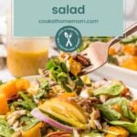 A fork holds a bite of fall salad with mixed greens, roasted squash, pecans, and apple slices on a white plate. A jar of dressing sits in the background, ready to drizzle over this colorful fall harvest salad.