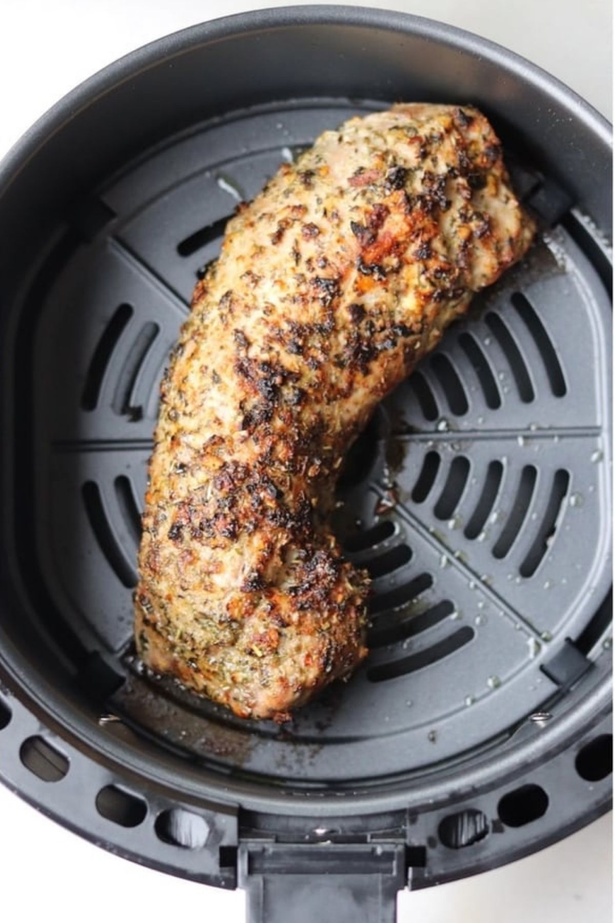 A perfectly cooked pork tenderloin in air fryer basket.