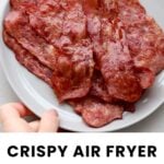 A plate of several slices of cooked turkey bacon with a hand holding the plate. Text below reads: "Crispy Air Fryer Turkey Bacon, cookathomemom.