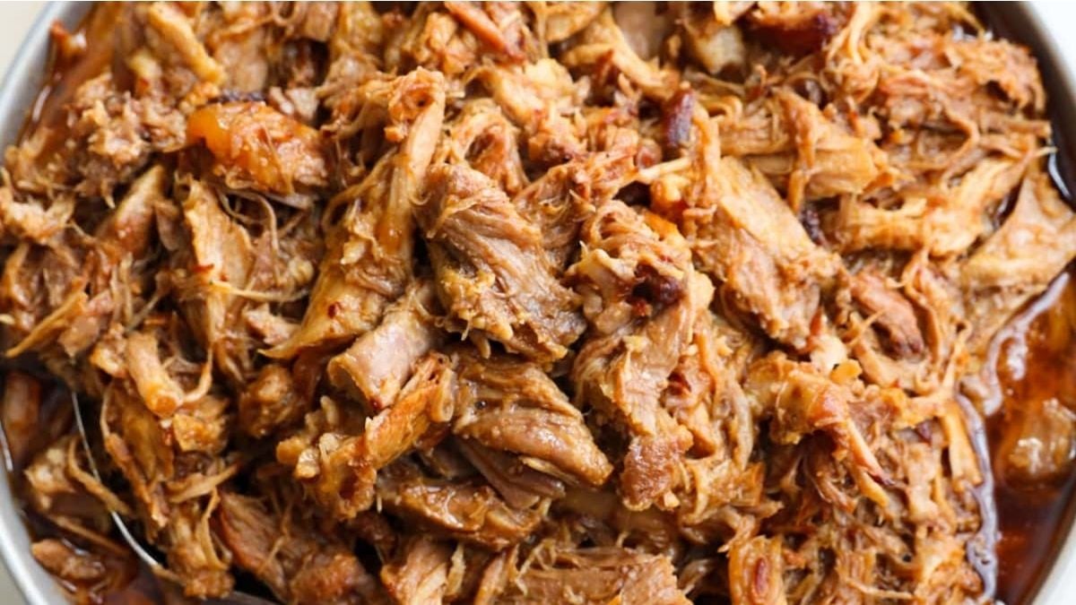 Shredded cooked pork in a bowl, coated with a brown sauce.