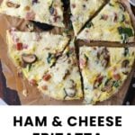 A sliced ham and cheese frittata with visible mushrooms and spinach on parchment paper, next to a knife.