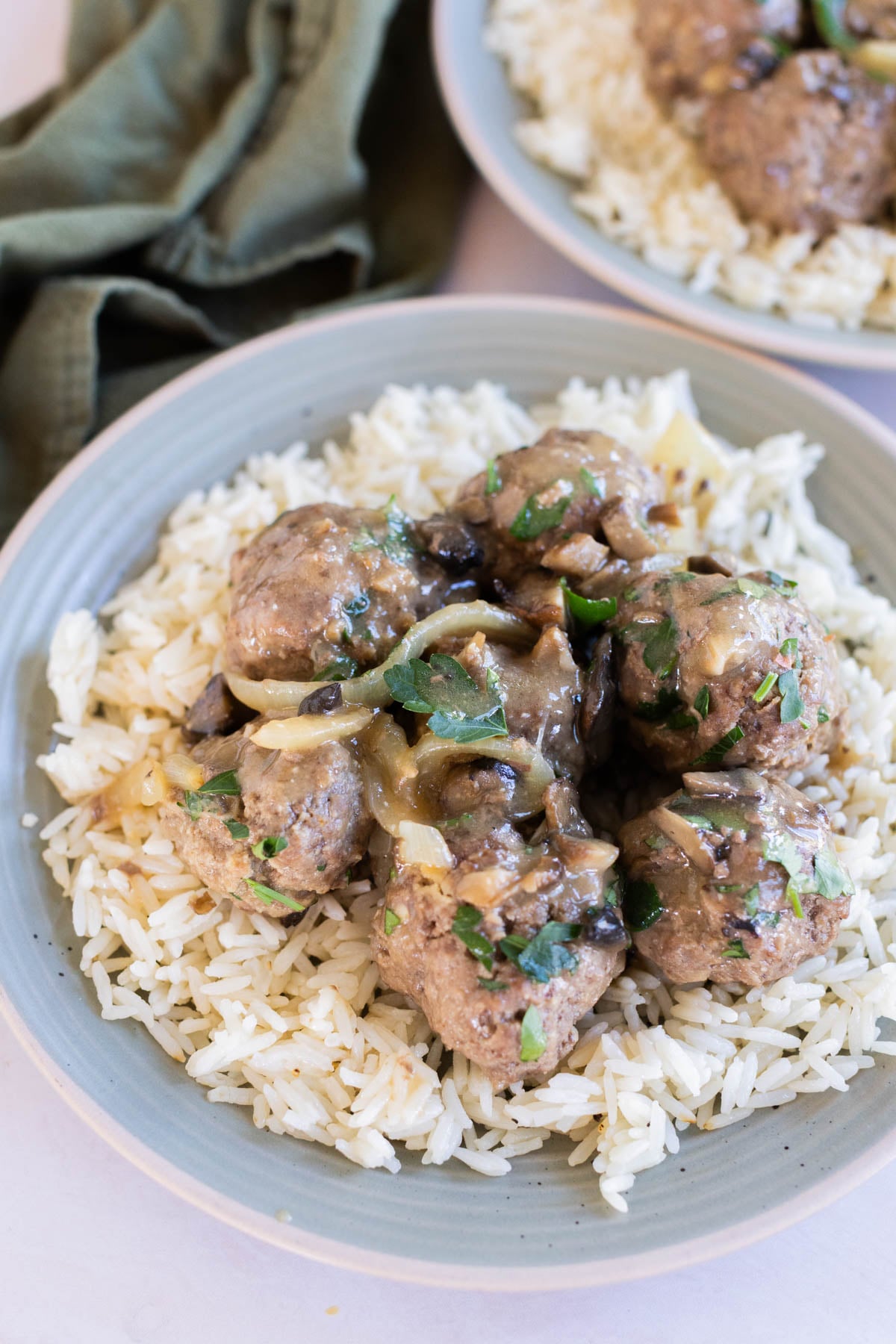 Salisbury steak meatballs with gravy served over white rice on a gray dinner plate, viewed from overhead.